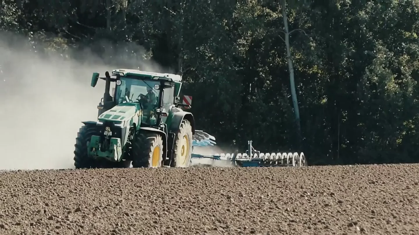 Prawdziwy ciągnik John Deere pracujący z pługiem na polu